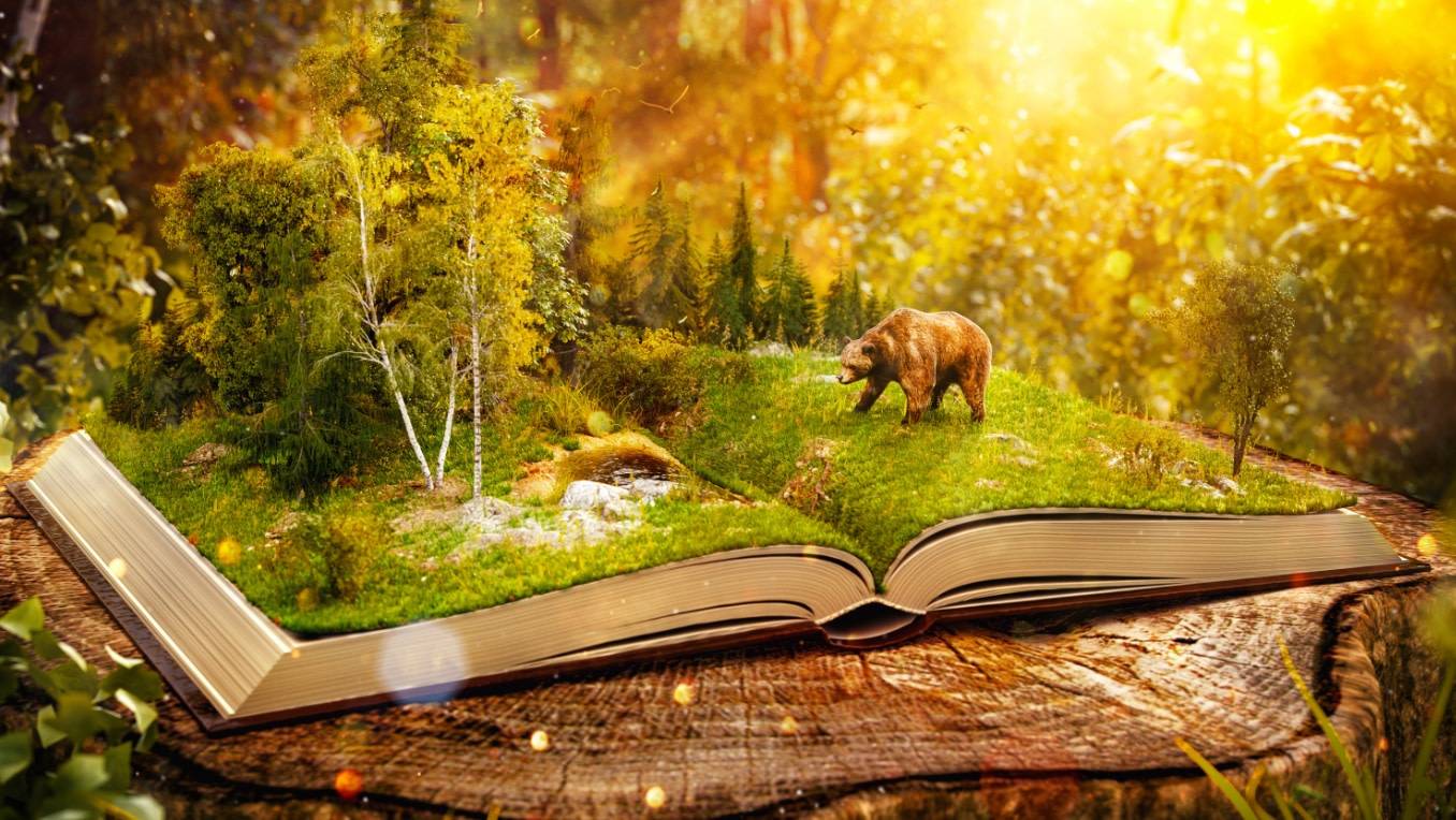 A fantasy scene: a miniature bear saunters across an open book, which is covered in grass and trees