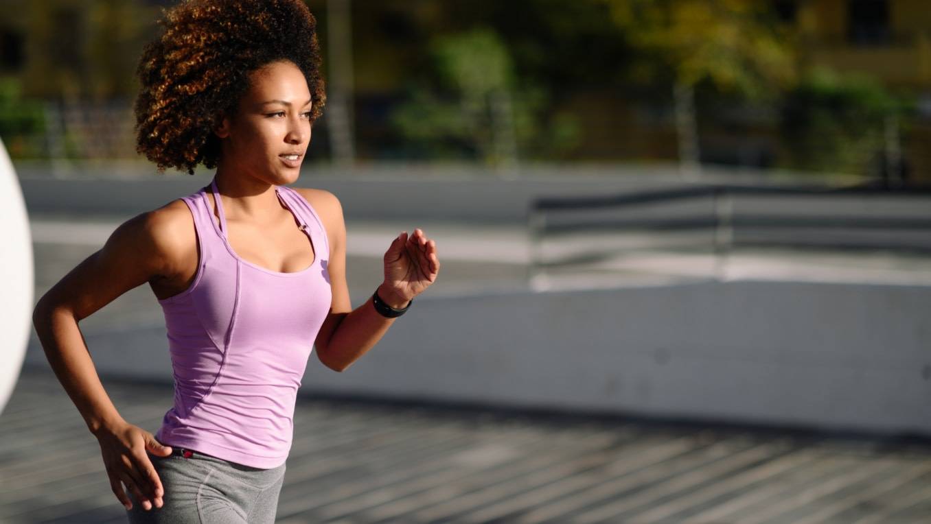 An image of a Black woman jogging while listening to audio content