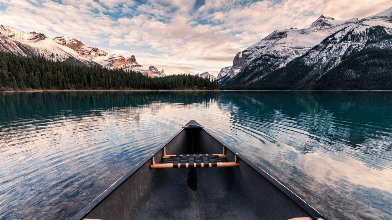 The image of a canoe on a tranquil lake near the mountains 