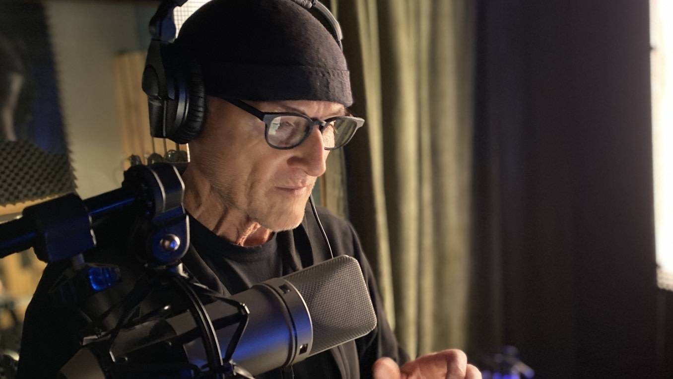 A photo of Colm Feore in a recording studio in front of a microphone