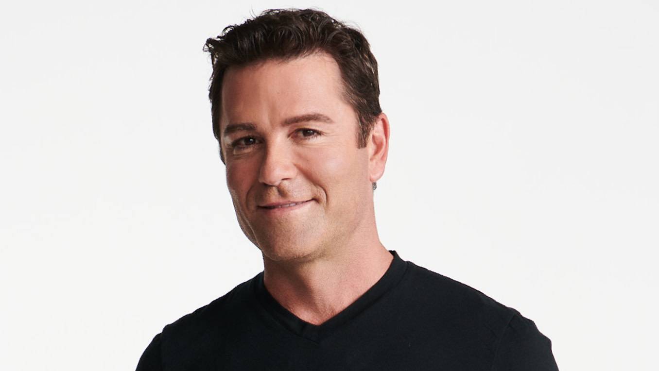 A portrait of a smiling Yannick Bisson in a black t-shirt