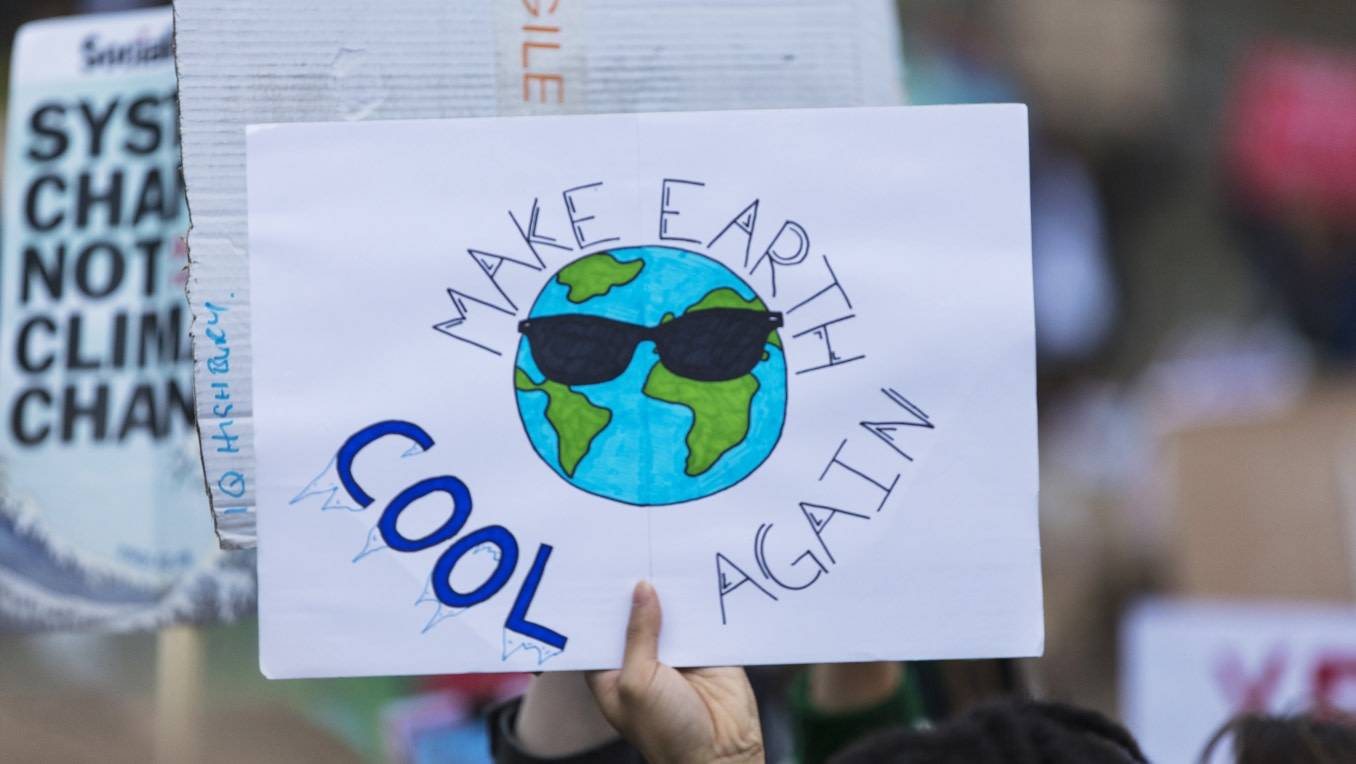A photo of a protest rally featuring signs about climate change