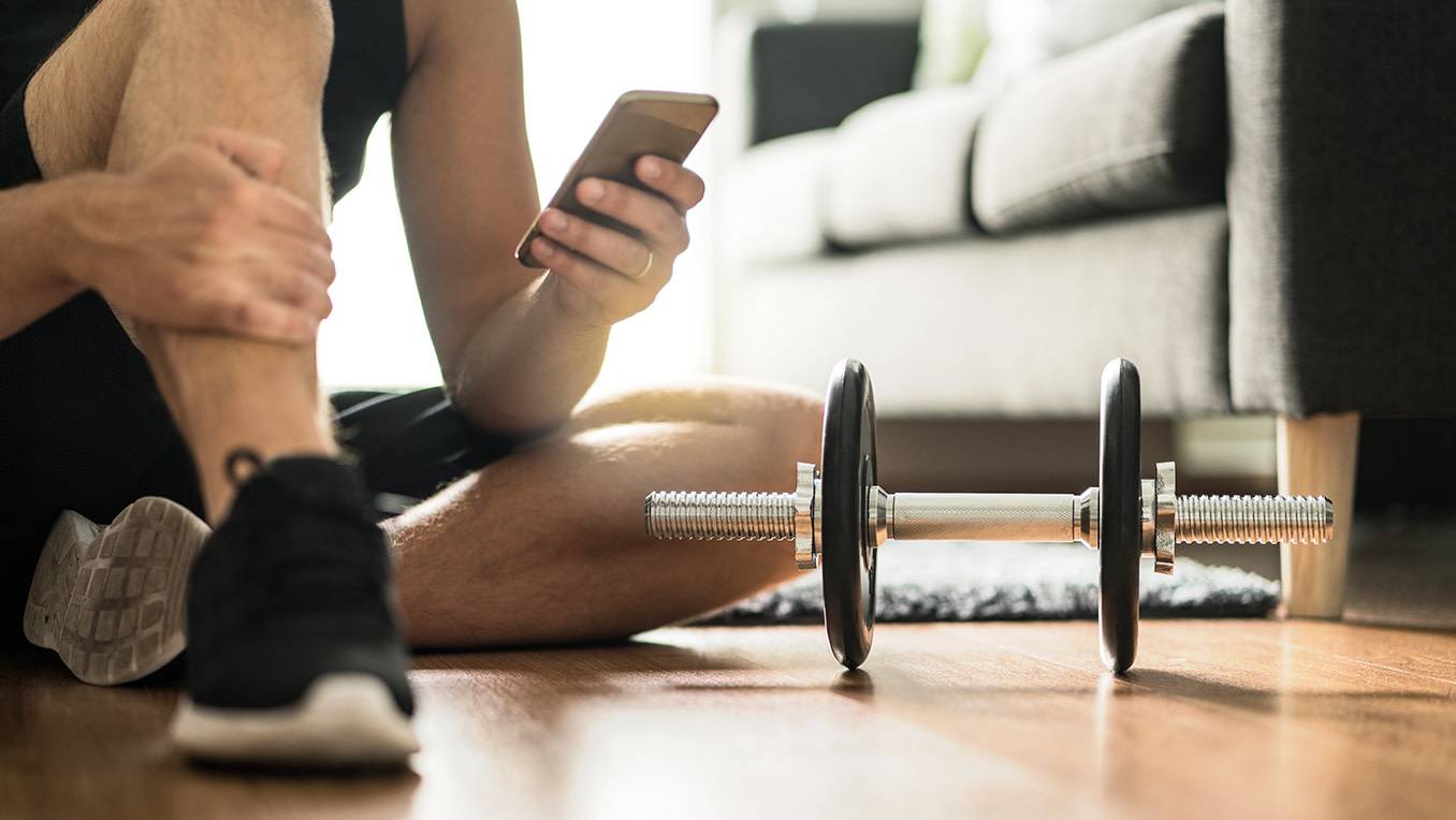Man using smartphone during at home workout  