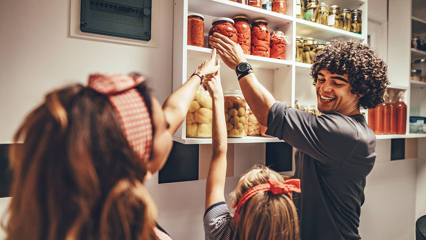 A father and his children select ingredients from a pantry