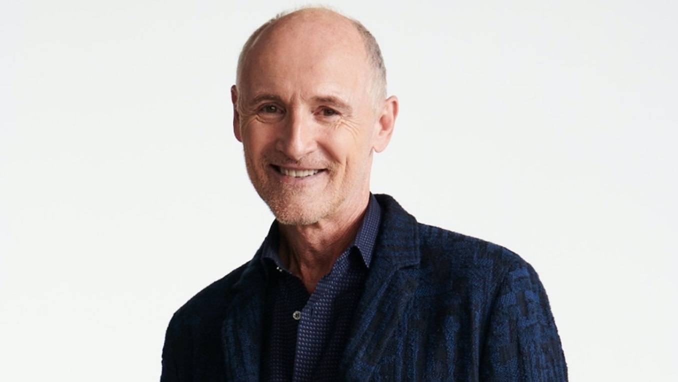 A portrait of Colm Feore in jeans and a navy blazer
