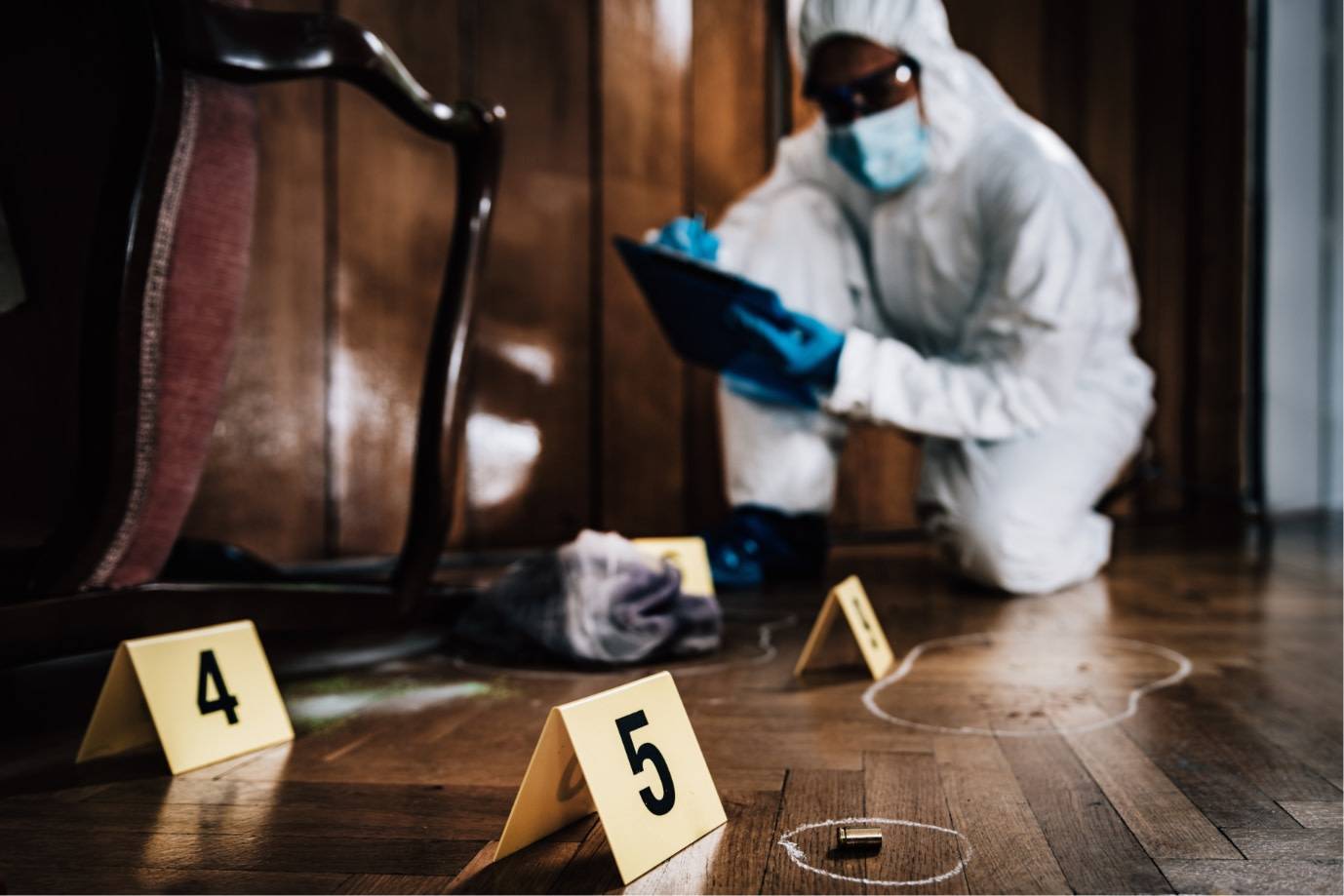 A photo of a crime scene with chalk outlines around bullet casings and a forensic detective in the background