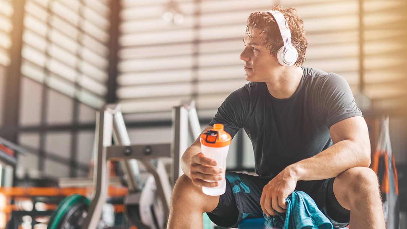 Homme au gym avec des écouteur en pause durant son entraînement