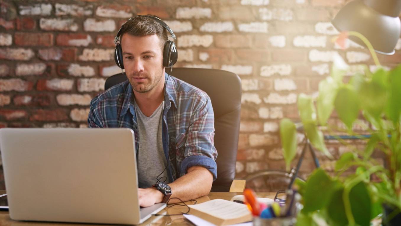 Un homme écoute des livres audio en travaillant à l’ordinateur