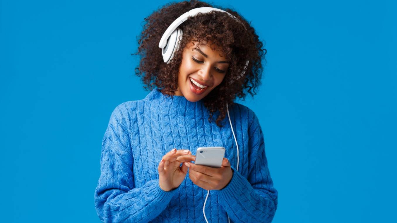 Une femme est heureuse de pouvoir écouter ses livres audio sur son cellulaire