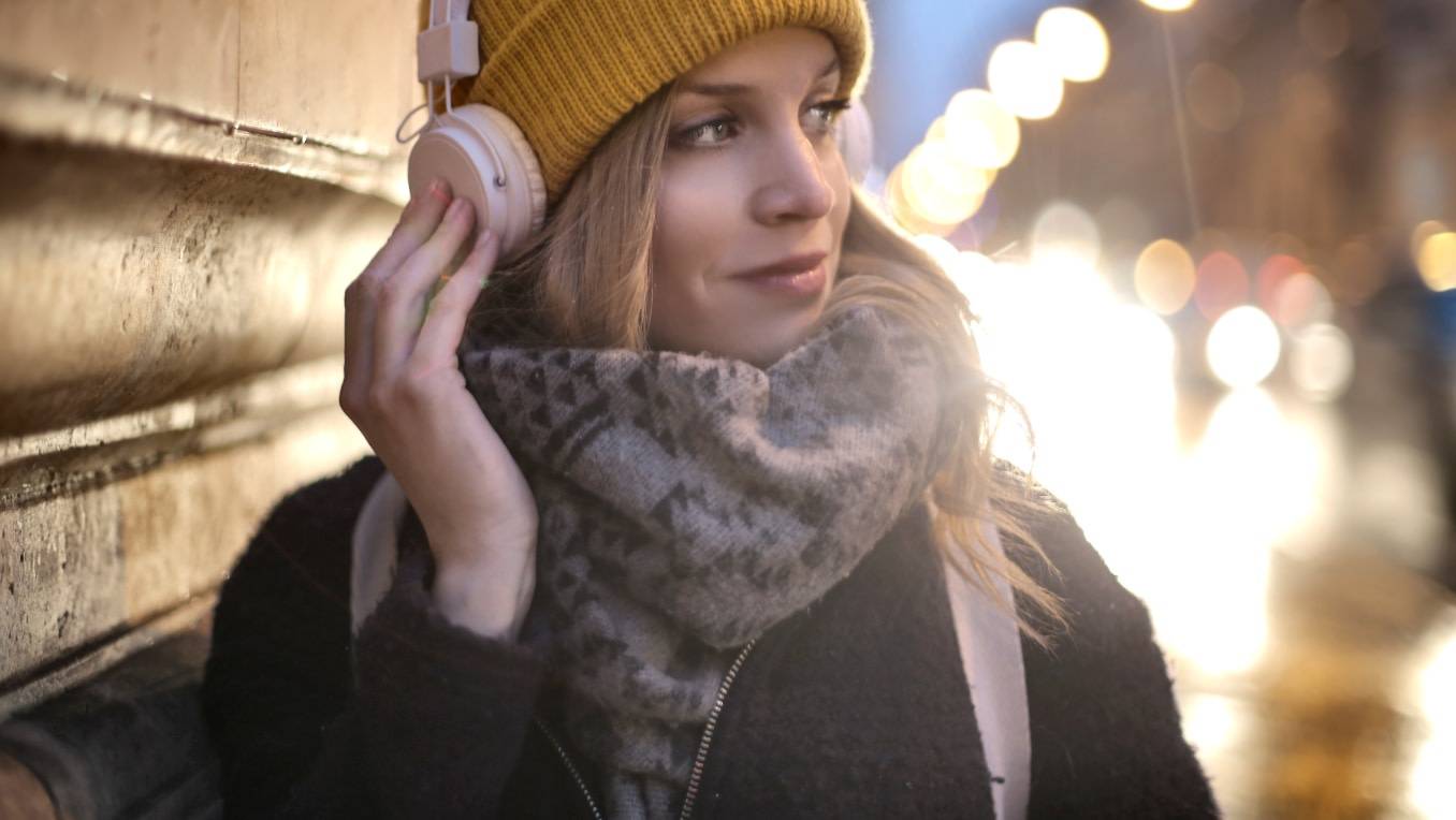Une femme dans la rue écoute des livres audio avec ses écouteurs